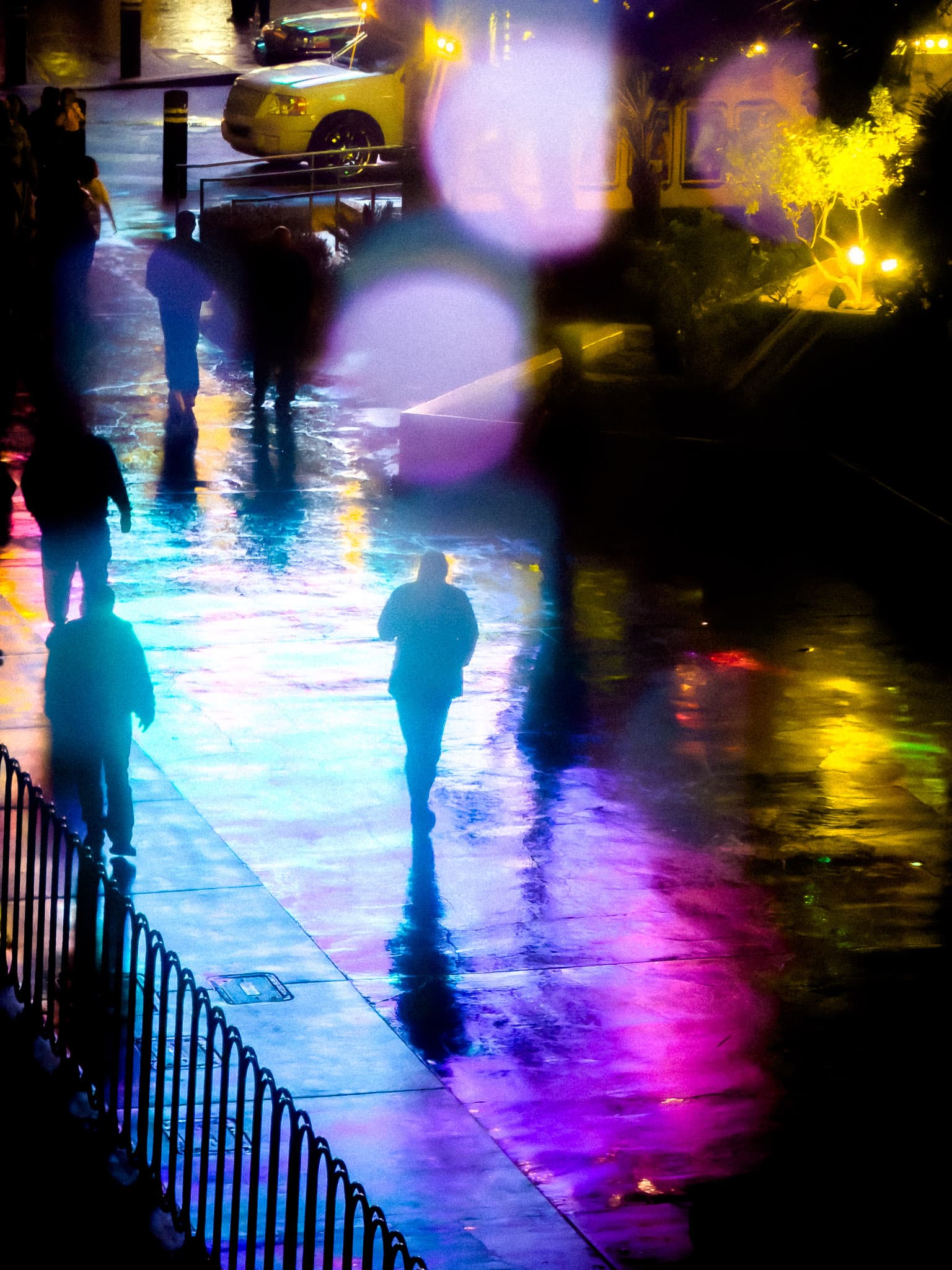 Neon light reflections on a wet city sidewalk at night